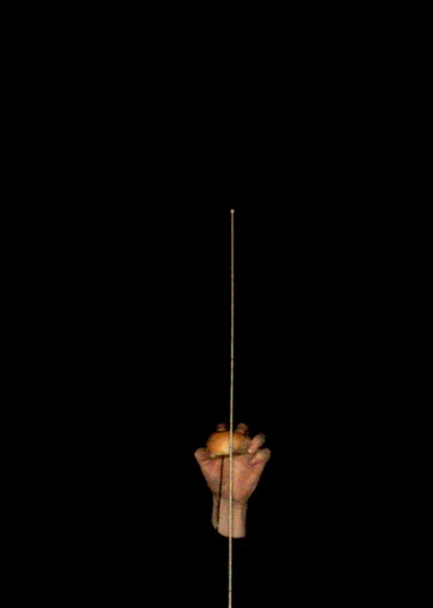A hand holding a bun beside a tall antenna against the night sky.