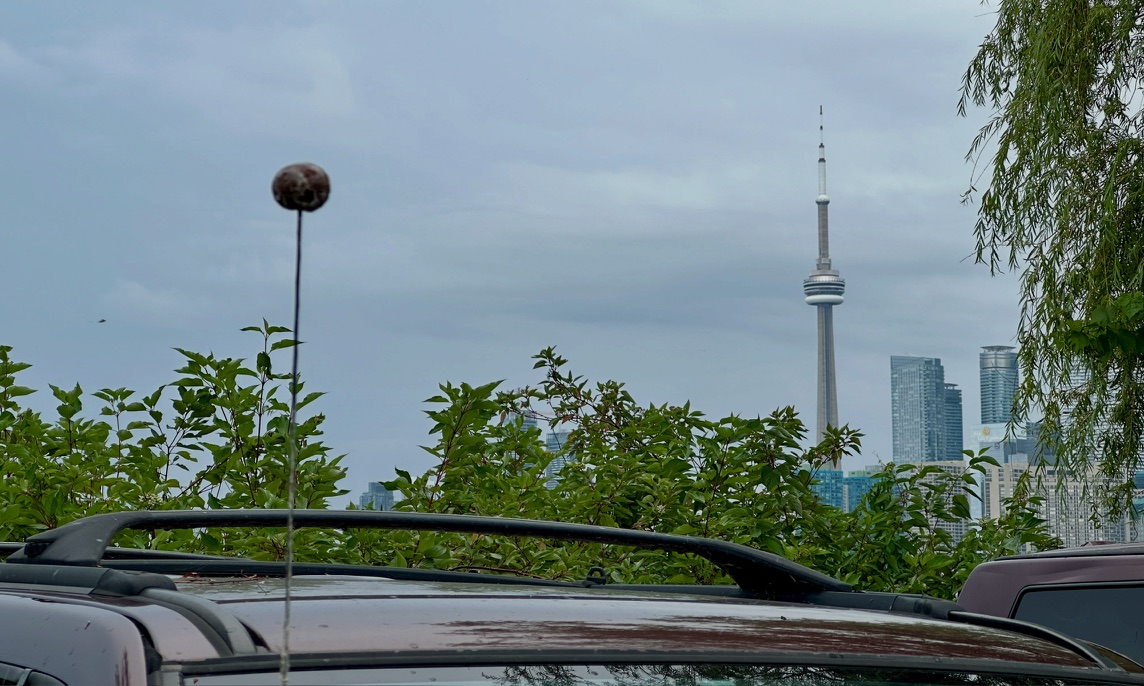 A bun-topped car antenna with Toronto's CN Tower in the distance.